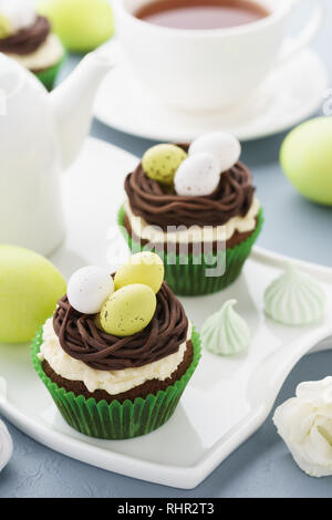 Easter chocolate cupcakes with nest, candy eggs and tea for dessert. Stock Photo