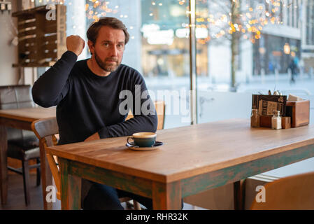 Angry middle aged caucasian male sitting at the table in coffee shop Stock Photo