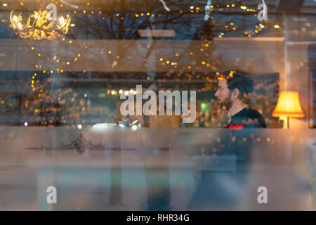 Handsome man with beard in coffee shop with lights reflecting Stock Photo