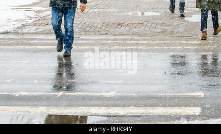 Winter City Slippery Sidewalk. Feet of people walking along the icy snowy pavement in crosswalk in snowfall. Pair of shoe on icy road in winter. Abstr Stock Photo