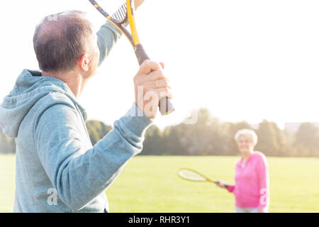 Senior man serving badminton in park on sunny day Stock Photo