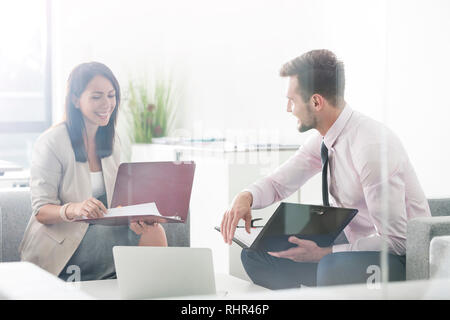 Smiling professionals discussing over documents in office Stock Photo