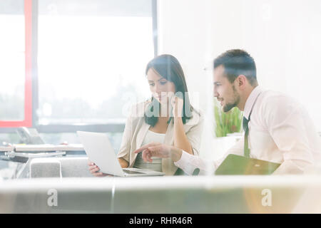 Confident professionals discussing over laptop in office Stock Photo