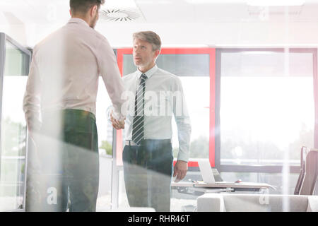 Businessmen shaking hands in office Stock Photo