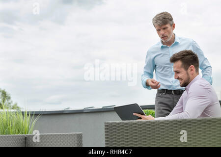 Colleagues communicating over digital tablet at office terrace Stock Photo