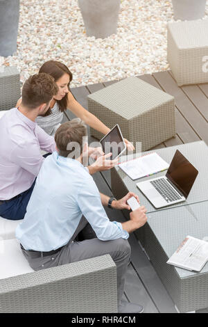 Business colleagues using technology sitting at office terrace Stock Photo