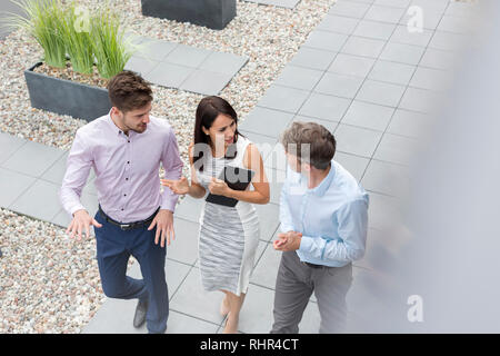 High angle view of professionals discussing while walking at office terrace Stock Photo