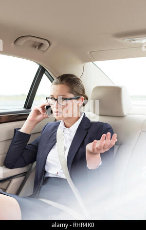 Businesswoman talking on smartphone in car Stock Photo