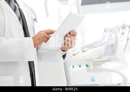 Midsection of doctor using digital tablet at dental clinic Stock Photo