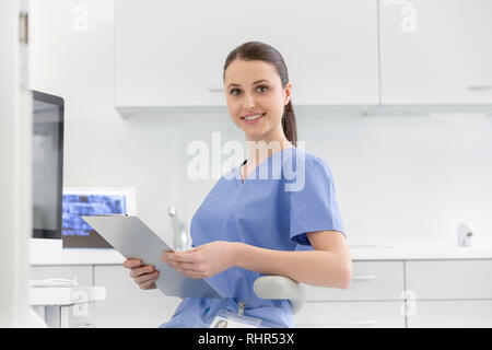 Portrait of smiling nurse with clipboard at dental clinic Stock Photo