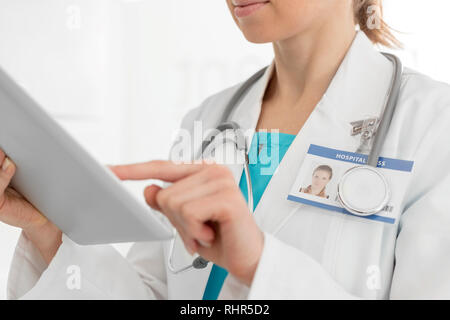 Midsection of female doctor using digital tablet at clinic Stock Photo