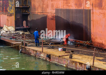 ship cleaning by jet water Work in floating dry dock the shipboard of the ship from sea vegetation before sandblast at cuxhaven Stock Photo