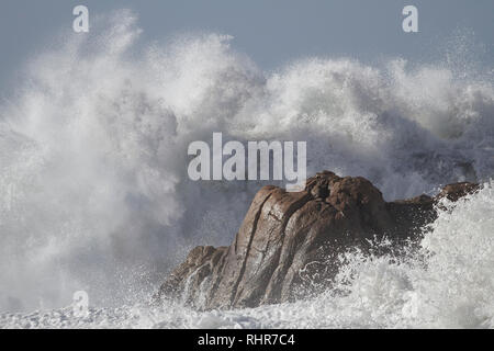Detailed huge stormy waves breaking over cliffs and rocks of the portuguese northern coast in a sunny evening. Stock Photo