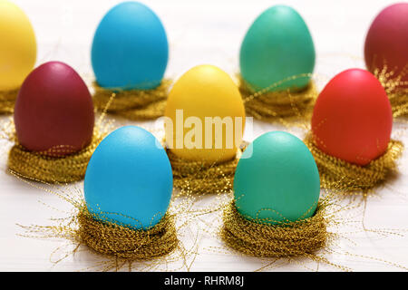 Multi-colored Easter eggs in nests of shiny gold threads Stock Photo