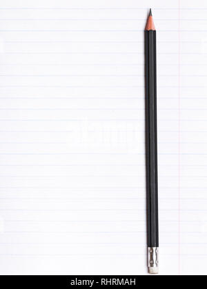 On a sheet of paper notebook with lines lies a black graphite pencil. Copy space. Education concept Stock Photo