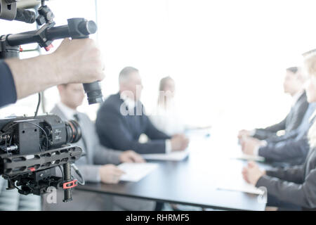 Videographer using steadycam, making video of business people at meeting Stock Photo