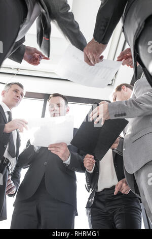 Group of business people work with documents at meeting standing near office window with view of city Stock Photo
