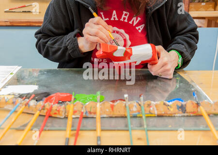 Mora, Sweden. 02/15/2017. Dala Horse factories of Nusnäs. In a workshop of carved Dalecarlian Horse. Employee is painting decoration on wooden horse. Stock Photo