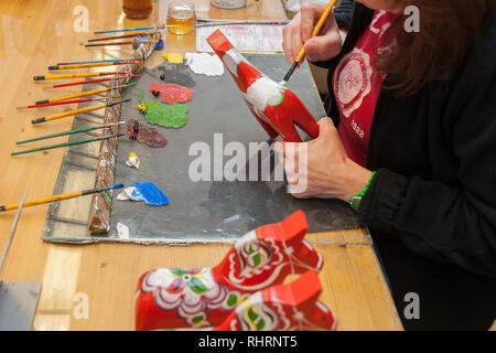 Mora, Sweden. 02/15/2017. Dala Horse factories of Nusnäs. In a workshop of carved Dalecarlian Horse. Employee is painting decoration on wooden horse. Stock Photo