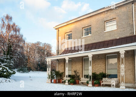 Decorative veranda with ornate wrought iron pillars and benches together with large pot plants on a snowy day in winter at Kenwood House, London Stock Photo