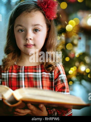 Closeup portrait of a cute and little girl holding a book Stock Photo