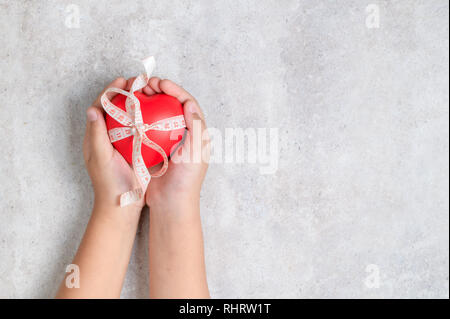 kid holding a red heart shape on marble table. Healthy balance and lose weight concept Stock Photo