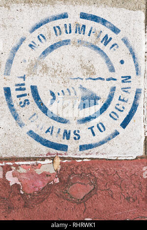 Sign above storm drain in Los Angeles, California which says 'No Dumping. This drains to ocean.' Stock Photo