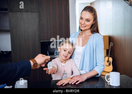 cropped view of broker giving house shaped key chain to cheerful mom and daughter Stock Photo