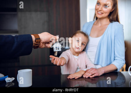 selective focus of broker giving house shaped key chain to cheerful mom and daughter Stock Photo