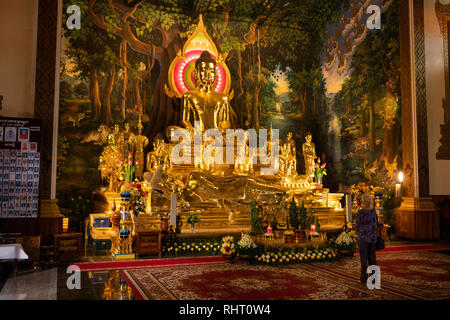 Cambodia, Phnom Penh, Wat Botum, inside Temple of Lotus Blossoms, visitor admiring gilded sitting and reclining Buddha figures Stock Photo