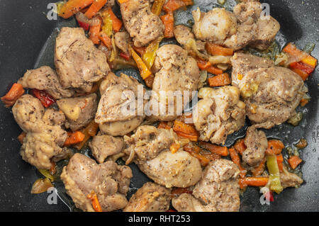 Top view on a pan with turkey meat pieces fried in sunflower-seed oil and vegetables Stock Photo