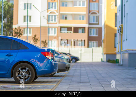 Side view detail of cars row parked in paved yard parking lot area on blurred building background on bright sunny day. Transportation and parking conc Stock Photo