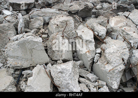 Fragments of concrete slabs in the form of large gray stones with protruding reinforcement. Background Stock Photo