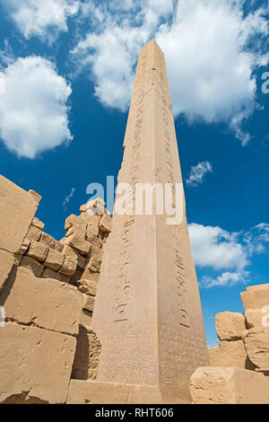 Large tall ancient egyptian obelisk at the temple of Karnak in Luxor with hieroglyphic carvings on blue sky background Stock Photo