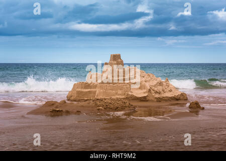 Big Sandcastle about to be destroyed by waves, Bamburgh Beach, Northumberland, UK Stock Photo