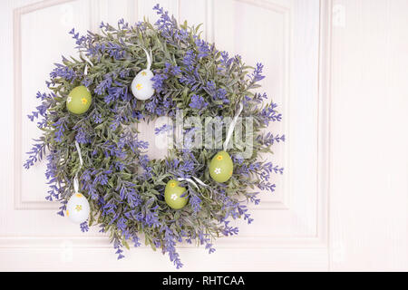 flower cornflower woven in a wreath with painted eggs hanging on the door on Easter Eve Stock Photo