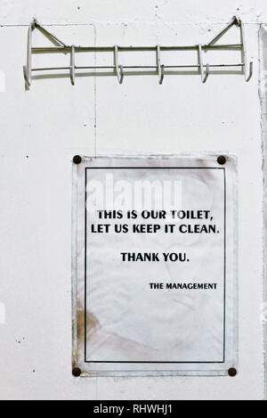 Toilet advisory sign, to keep the bathroom clean, hanging at a white painted wall of a toilet in a cheap pension house in Palawan, Philippines Stock Photo
