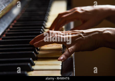 Close up fingers of woman pianist at the rusty piano keys, arms plays solo of music. Hands of female musician playing. Music instrument, solo pian Stock Photo