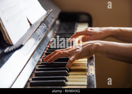 Close up fingers of woman pianist at the rusty piano keys, arms plays solo of music. Hands of female musician playing. Music instrument, solo pian Stock Photo