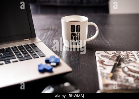 still life with blocknote, labtop, pen and a white mug of coffee over a black office desk. symbol of job Stock Photo