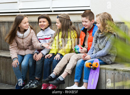 Active little boys and girls sharing secrets as talking outdoor Stock Photo