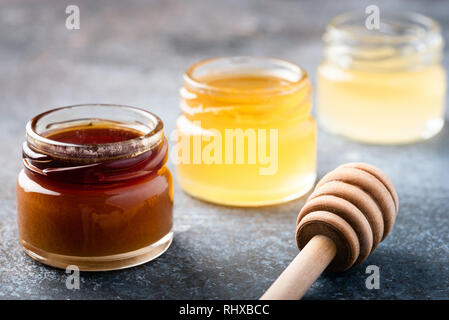 Assortment of honey in jars and wooden honey dipper. Closeup view Stock Photo