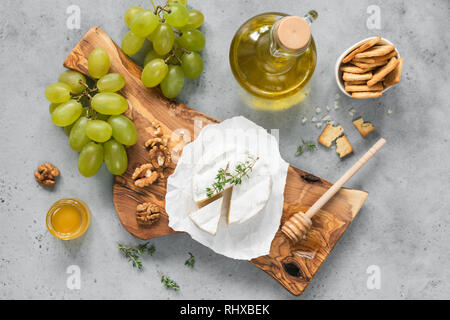 White cheese plate with crackers, honey, grapes. Assortment of wine snack, appetizer or gourmet dinner. Top view Stock Photo