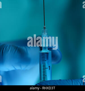 Physician injector arms in sterile uniform holding syringe Stock Photo