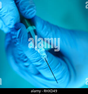 Physician injector arms in sterile uniform holding syringe Stock Photo