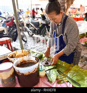 Woman making traditional read bean pancakes, Friday morning market, Chiang Mai Stock Photo