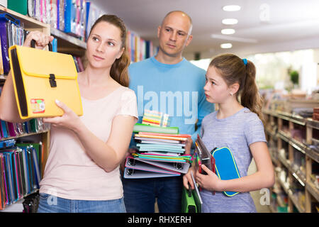 Loving parents with little daughter buying school supplies in stationery store Stock Photo