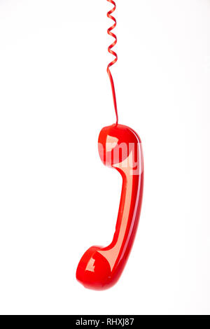 A red telephone handset hanging from it's cord. Stock Photo