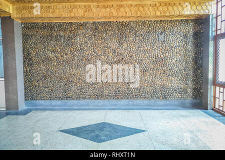 A masonry wall made up of pebbles and round stones with wooden ceiling. light coming from windows. Floor made up of mosaic Stock Photo