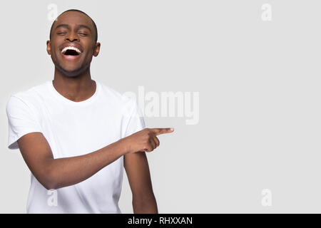 Happy african man laughing pointing finger aside at copy space Stock Photo